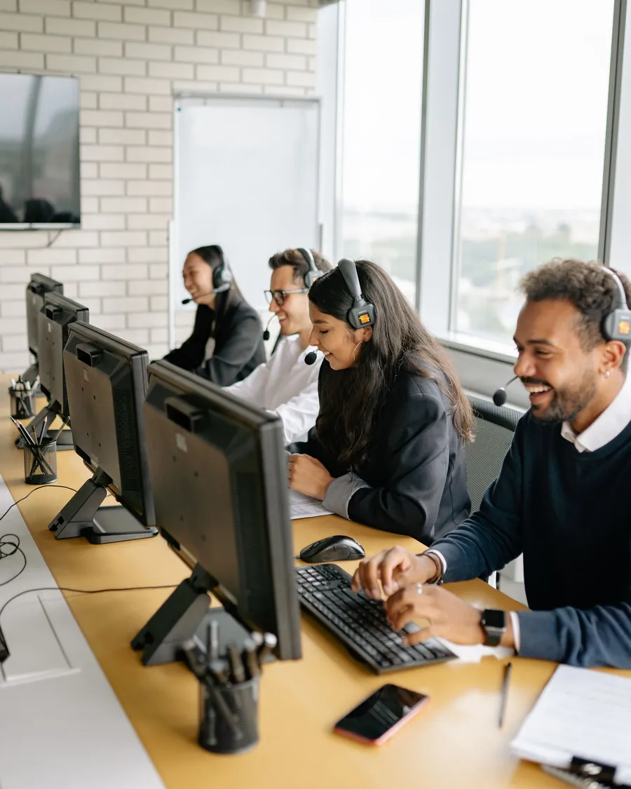 Agents with headsets at a row of desks with monitors