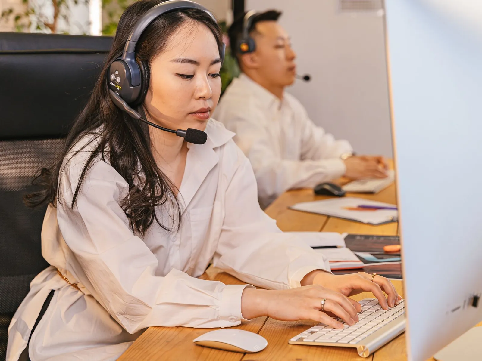 Call centre agents wearing headsets working at desktop computers in a modern office