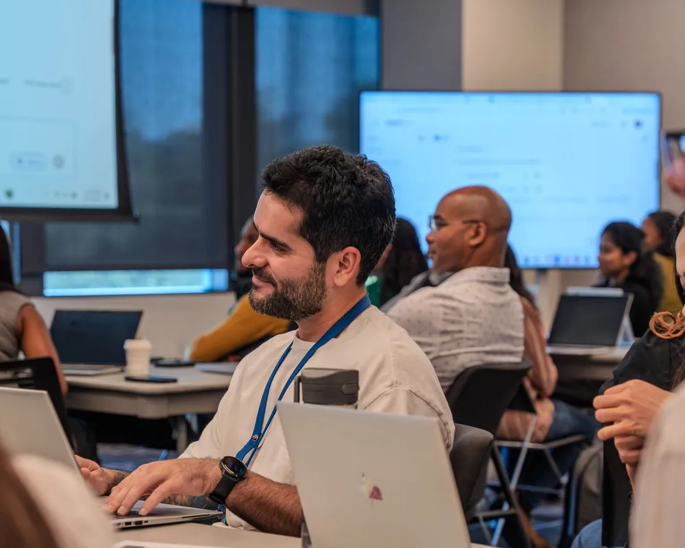 A training session with people working on laptops in front of presentation screens